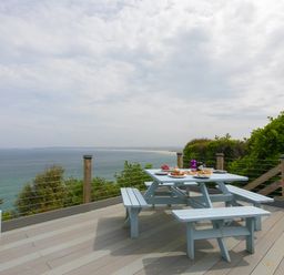 A deck with a picnic table and bench seating overlooking the ocean at Moonbeams in Carbis Bay