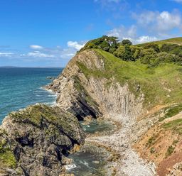 A rocky coastline with cliffs and vegetation beside the sea at West Lulworth Apartment in West Lulworth