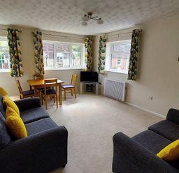 A living room with sofas, a table and a television at West Lulworth Apartment in West Lulworth