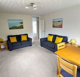 A living room with sofas and a table at West Lulworth Apartment in West Lulworth