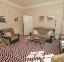 A sitting room with three sofas a glass coffee table and framed pictures on the walls at Lonsdale Villa Scarborough