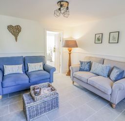 A sitting room with two sofas a floor lamp and wicker baskets at Blossom Cottage in Broadway