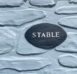 A black oval sign with the word stable on a textured light blue wall at The Stable @ Canllefaes Penparc near Cardigan