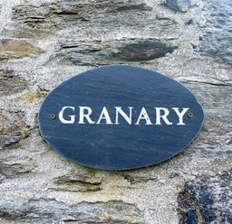 A stone wall with a dark oval plaque reading GRANARY at The Granary @ Canllefaes in Penparc near Cardigan