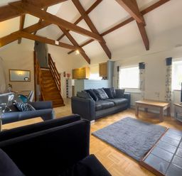A living room with sofas a coffee table and a TV near windows and stairs at The Granary @ Canllefaes in Penparc near Cardigan