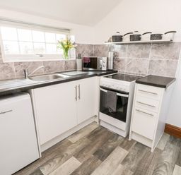A kitchen with a sink microwave stove pots and drawers at Hawthorn Dale Cottage in Whitby