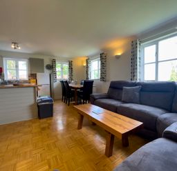 An open living space with a dining table, kitchen area, sofa, and coffee table at The Wheel @ Canllefaes in Penparc near Cardigan