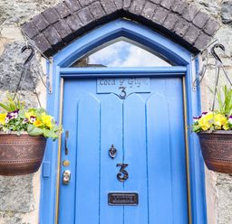 A blue door with the number 3 and flower pots hanging on both sides at Coed Y Glyn in Llanuwchllyn near Bala