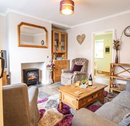 A living room with armchairs a sofa a wooden cabinet a coffee table and a fireplace at Coed Y Glyn Llanuwchllyn near Bala