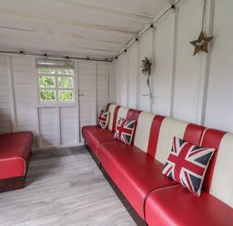 A small room with red and white striped benches and Union Jack pillows at Wyvill House in Cayton
