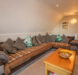 A living room with a large sectional sofa and wooden coffee table at Hillside in Gunnislake