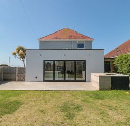 A backyard with a lawn patio and glass doors on a modern house at Fisherman's Rest in Wyke Regis