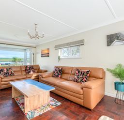 A living room with two brown leather sofas a wooden coffee table and a potted plant at Beach Haven in Polzeath