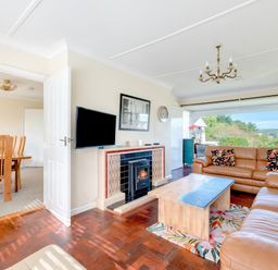 A living room with leather sofas and a coffee table near a window at Beach Haven in Polzeath