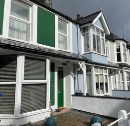 A row of terraced houses with bay windows and different colored facades including green and blue at Alltwen in Borth-y-Gest