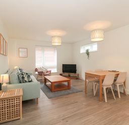 A living room with a sofa coffee table and dining table at Apartment 1 in Exmouth