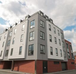 A modern four-story apartment building with multiple windows and a brick base at Apartment 9 in Exmouth