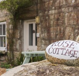 A stone with Rose Cottage written on it in front of a stone cottage with a white door and window at Rose Cottage Lower Bostraze near St Just