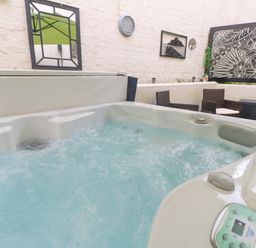 A hot tub with seating area and decorative features at Driftwood in Marazion