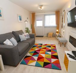 A living room with a sofa and rug at Driftwood in Marazion