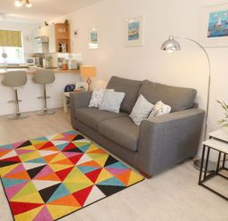 A living room with a sofa and colorful rug at Driftwood in Marazion