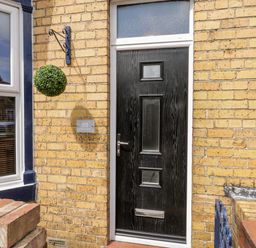 A black front door with a mail slot and frosted window panels on a yellow brick wall at 89 Caledonia Street Scarborough