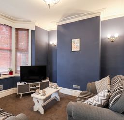 A living room with a gray sofa and a TV on a stand beside a white coffee table at 89 Caledonia Street in Scarborough