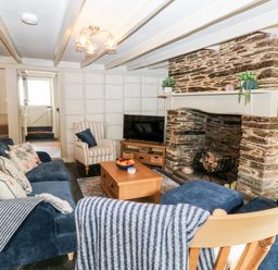 A living room with blue sofas a stone fireplace and a wooden coffee table at Alexanders Cottage in Frogmore