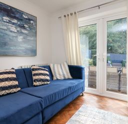 A living room with a blue sofa with cushions and glass doors opening to a garden at 4 Woodland Park in Northam