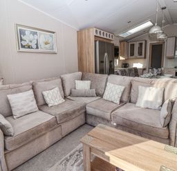 A living room with a corner sofa and a wooden coffee table next to an open kitchen with dining table at Owl's Nest in Newton on Derwent near Wilberfoss