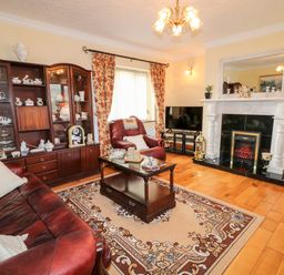 A living room with brown leather sofas a wooden cabinet with china a fireplace a television and floral curtains at Derriens Farmhouse Letterbreen County Fermanagh
