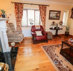 A living room with a fireplace armchairs a coffee table and floral curtains at Derriens Farmhouse Letterbreen County Fermanagh