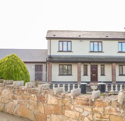 A two-story house with a stone wall and bushes in front at Derriens Farmhouse in Letterbreen County Fermanagh