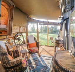 An outdoor seating area with two wooden chairs and a table beside a rustic wagon at The Wagon at Burrow Hill in Ottery St Mary