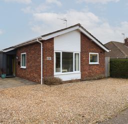 A single-story brick house with a gravel driveway and small bushes at The Lobster Pot in Overstrand