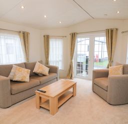 A living room with a sofa armchair coffee table and windows with curtains at The Bobbin Number 11 South Lakeland Leisure Village near Carnforth