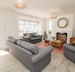 A living room with grey sofas a coffee table a fireplace and a television at Greenbank in Woolacombe