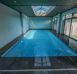 An indoor swimming pool with glass ceiling panels and large windows at Nightingales in Bridlington