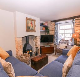 A living room with a fireplace and sofa at Mallards in Bourton-On-The-Water