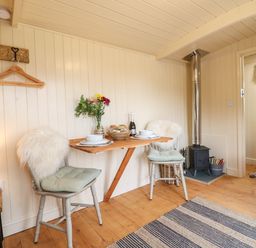 A small dining area with two chairs a wooden folding table and a stove in a room at High Grounds Shepherd's Hut Boylestone near Ashbourne