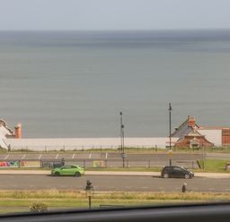 A coastal view with parked cars facing the sea at Foxton Penthouse in Whitby