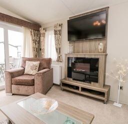 A living room with an armchair and a television above an electric fireplace at Number 10 in Warton