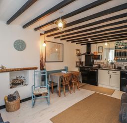 A living room with a dining area and kitchen appliances at Menuchah in Criccieth