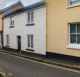 A street view of adjoining houses with white and yellow exteriors and windows at Hope Cottage in Buckfastleigh