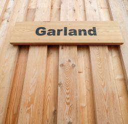 A wooden sign with the word Garland mounted on a vertical wooden plank wall at Garland in Nottington near Weymouth