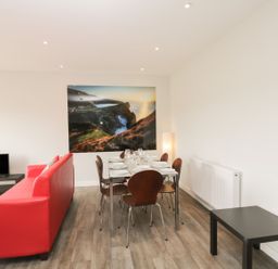 A dining area with a table set for six and a red sofa in a living room at Lulstead in Nottington near Weymouth