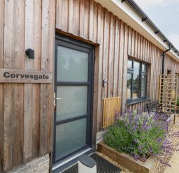 An outdoor entry area with a wooden exterior and a plant bed at Corvesgate in Nottington near Weymouth
