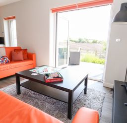 A living room with an orange sofa and coffee table at Corvesgate Nottington near Weymouth