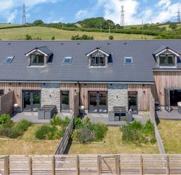 A row of modern townhouses with fenced gardens and outdoor seating at Dirdale in Weymouth