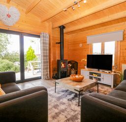 A living room with a wood stove and television at Howgills Retreat in Gatebeck near Kirkby Lonsdale